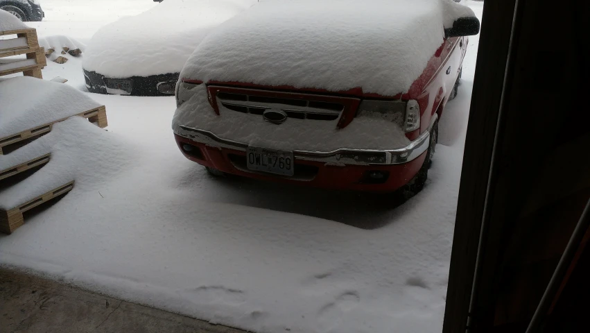 a parked truck covered in snow on the sidewalk