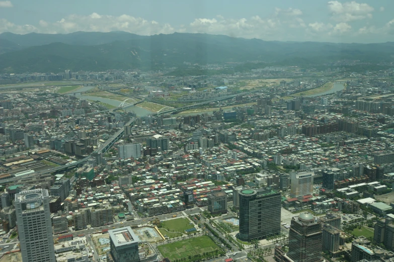 a city filled with lots of tall buildings and lush green hills in the distance