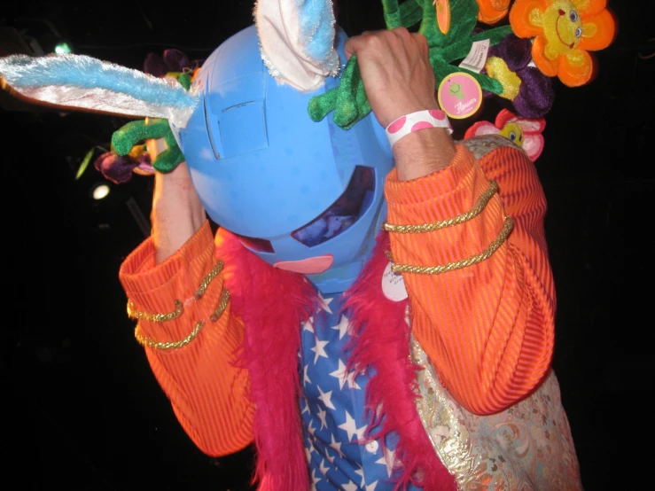 the masked person is putting on a colorfully decorated hat