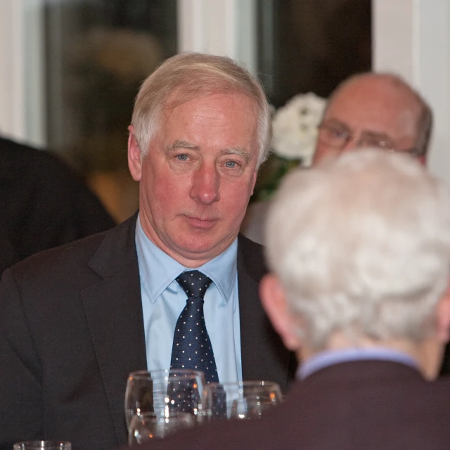 two men and one woman are sitting at a dinner table talking