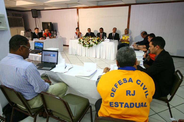 group of people seated around a table listening to a presentation
