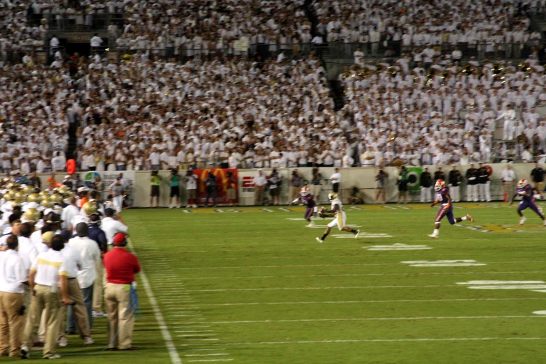 many people watching a football game in front of a full crowd