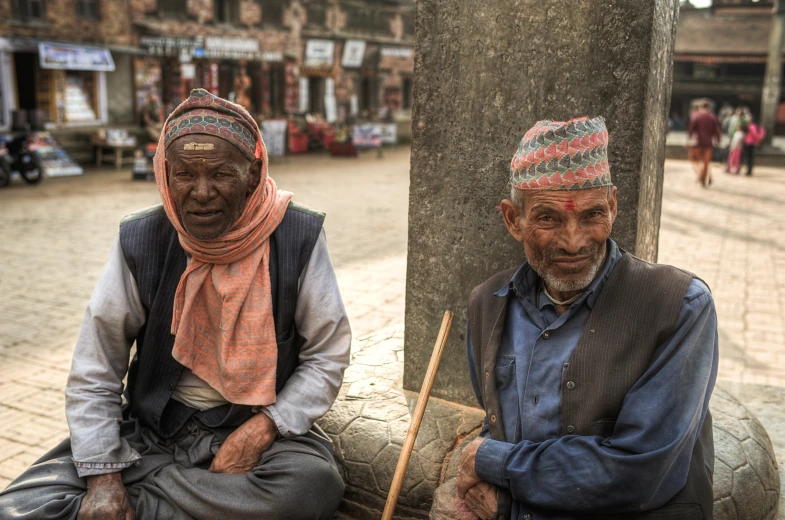 two men sitting together outside on a sunny day