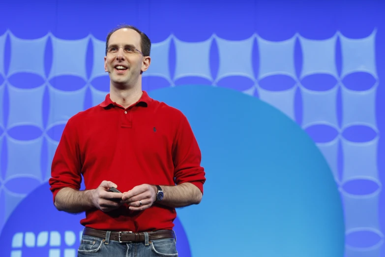 a man in a red shirt speaks while wearing a smart watch