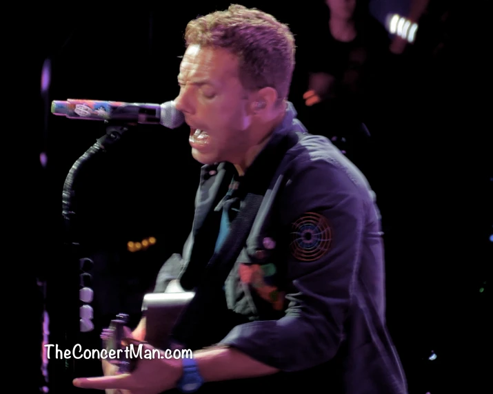 man in black vest singing into a microphone