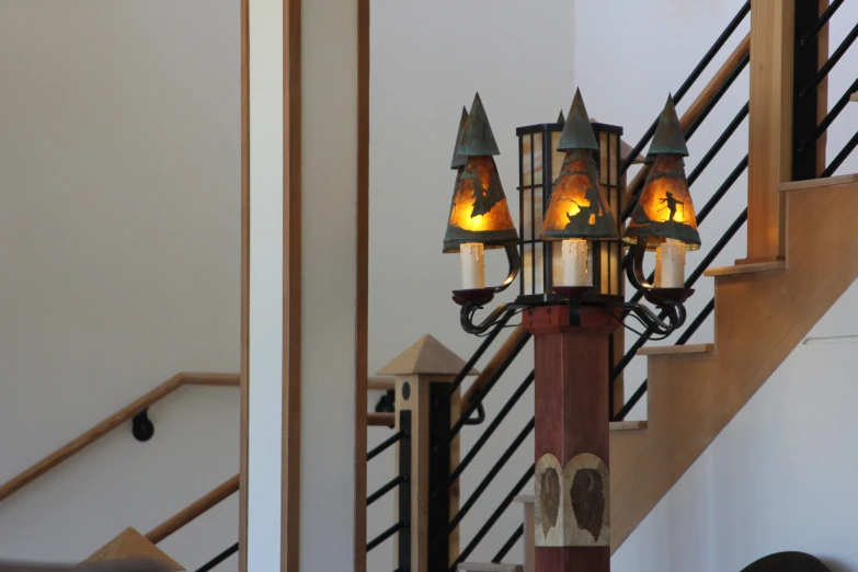 a metal lantern is on a wooden railing next to an iron hand rail and a staircase