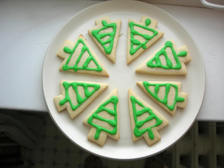 some cookies are decorated with green icing on a plate