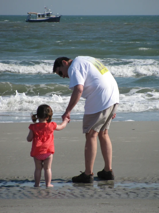 an older man and young child holding hands on a beach