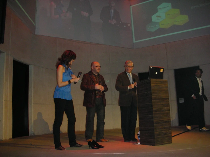 several people standing and talking with a projection screen in the background