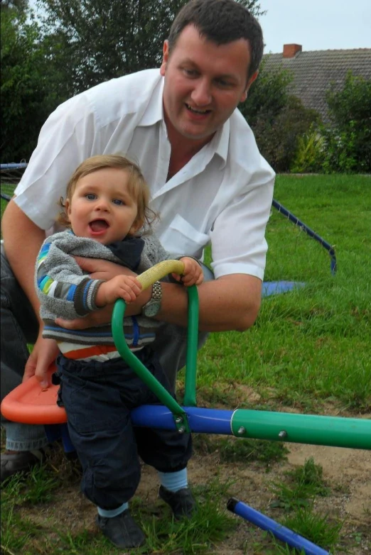 a man holding a young child while standing in a yard