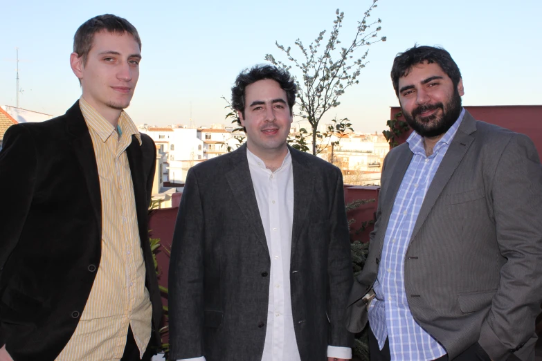 four men, two of whom are dressed in business attire, are smiling for the camera