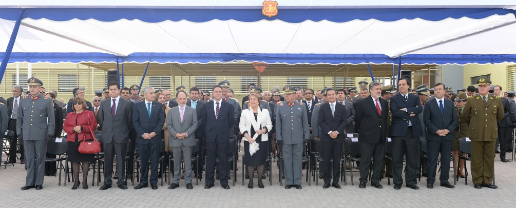 men and women wearing suits standing together under a tent