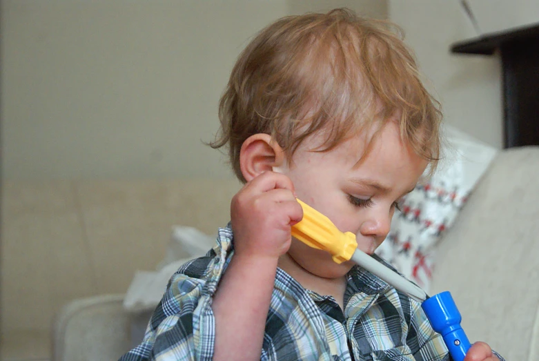 a little  that is holding a toothbrush in his hand