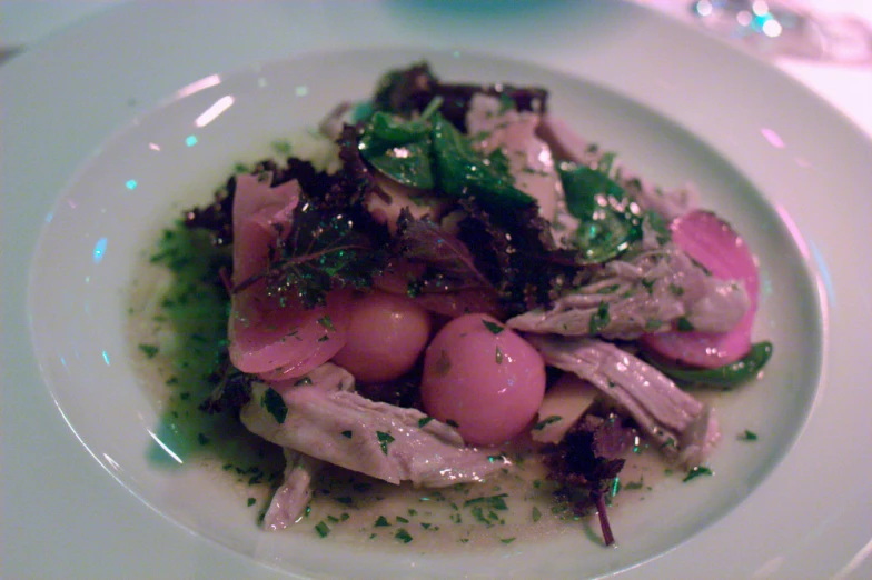 a white plate with tuna salad with onions and garnishes