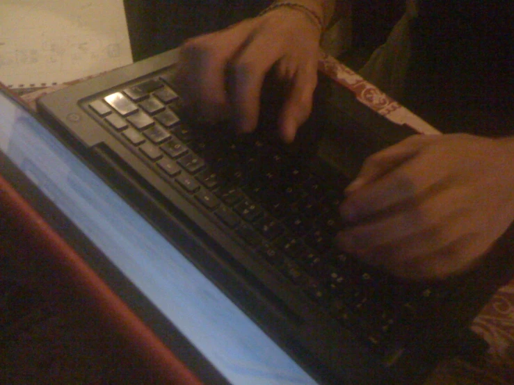 someone typing on their laptop keyboard while holding a tape