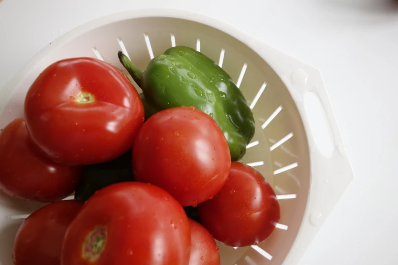 tomatoes, peppers and jalapenos are sitting in a bowl
