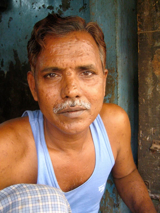 an old man sits in front of the door of his home