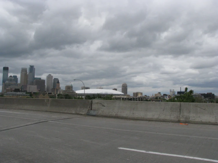 an empty street with a fence and skyline in the background