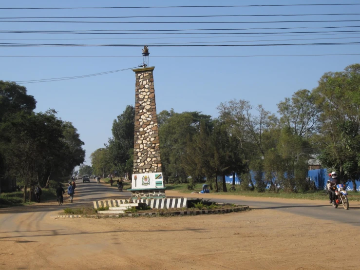 a man on his bike rides past a tall monument