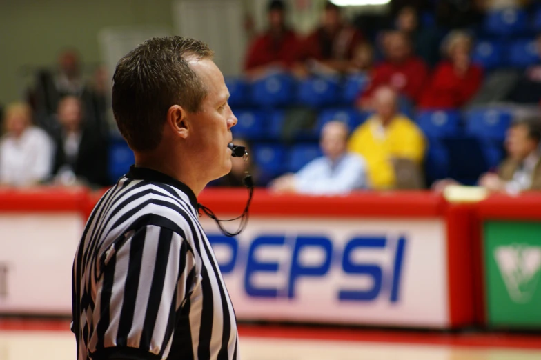 a referee looks at a match with people on the sidelines