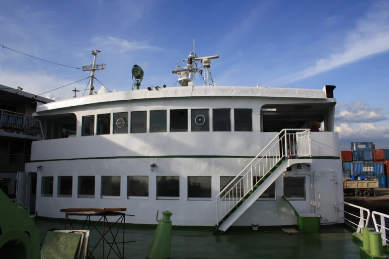 a white ship with two decks next to some dock