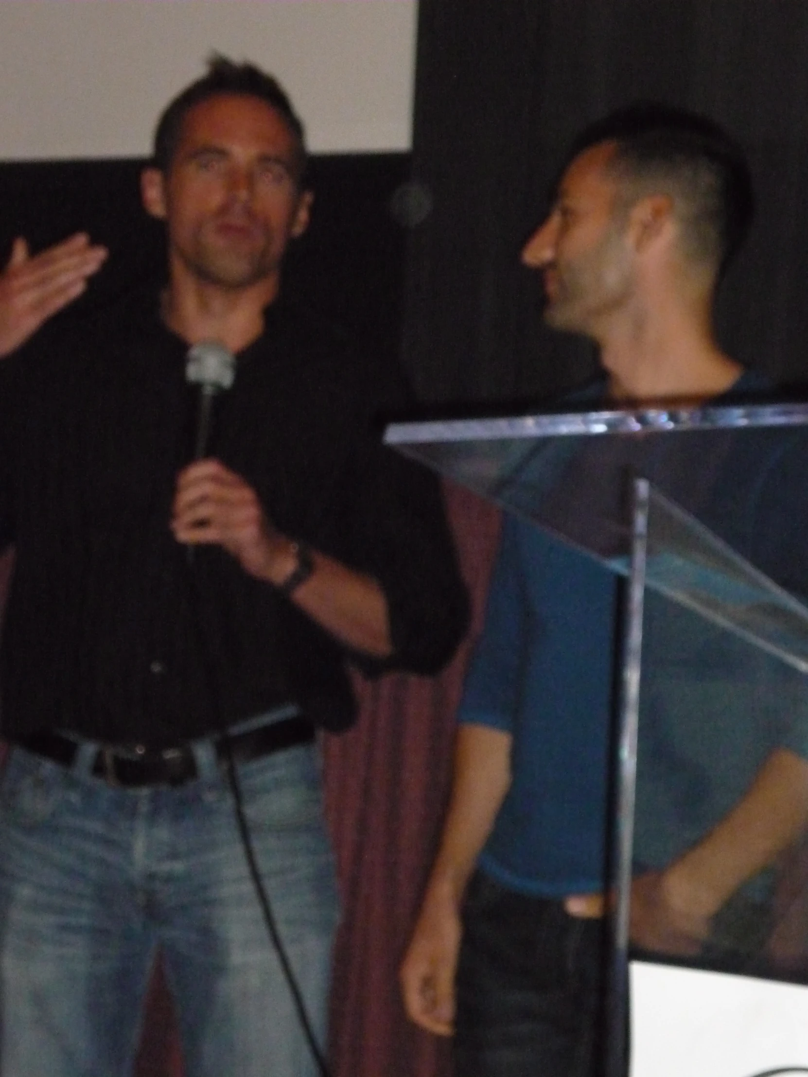 two men with microphones in front of a screen