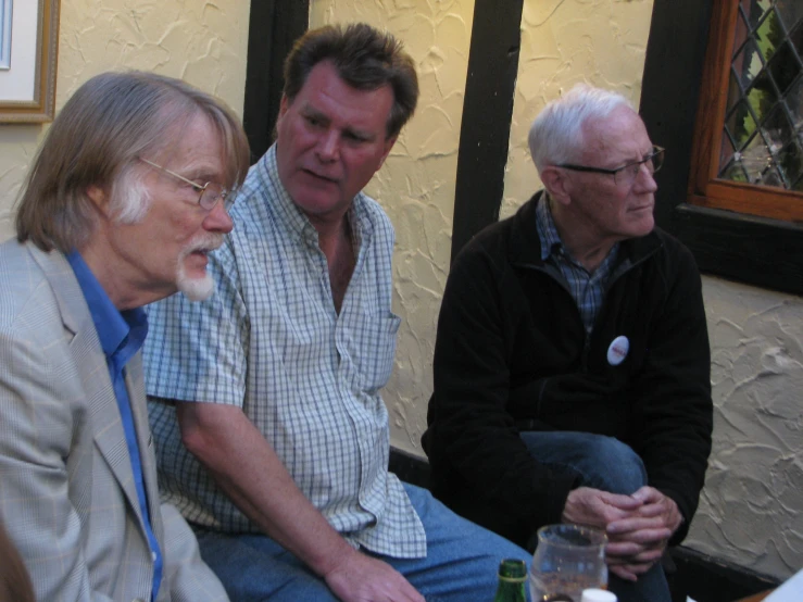 three older men sitting next to each other at a table