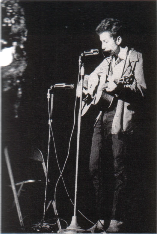 a man standing at the microphone with a guitar