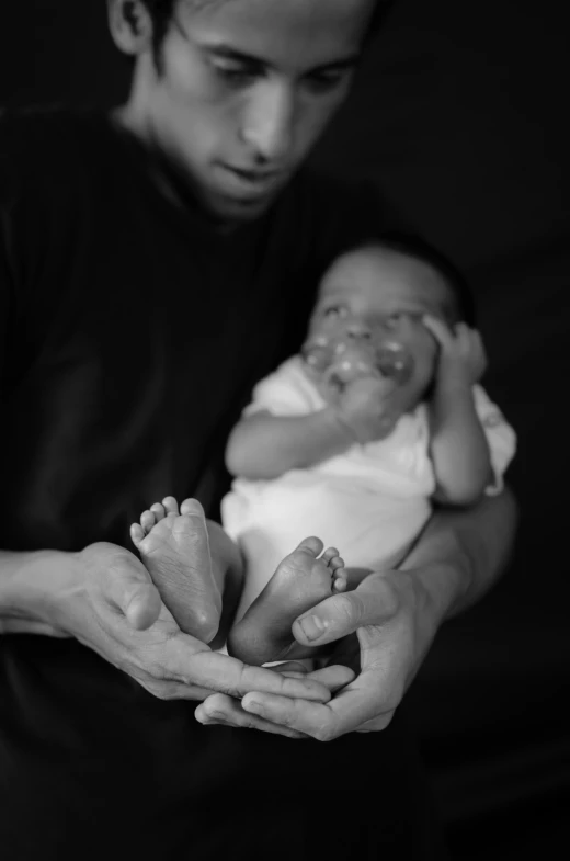 a young man holding a baby in his hands