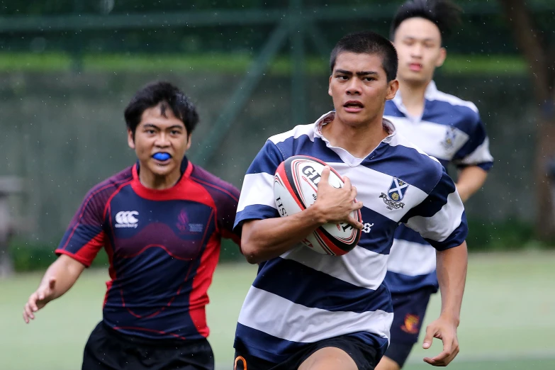 three men in striped shirts running and one holding a ball