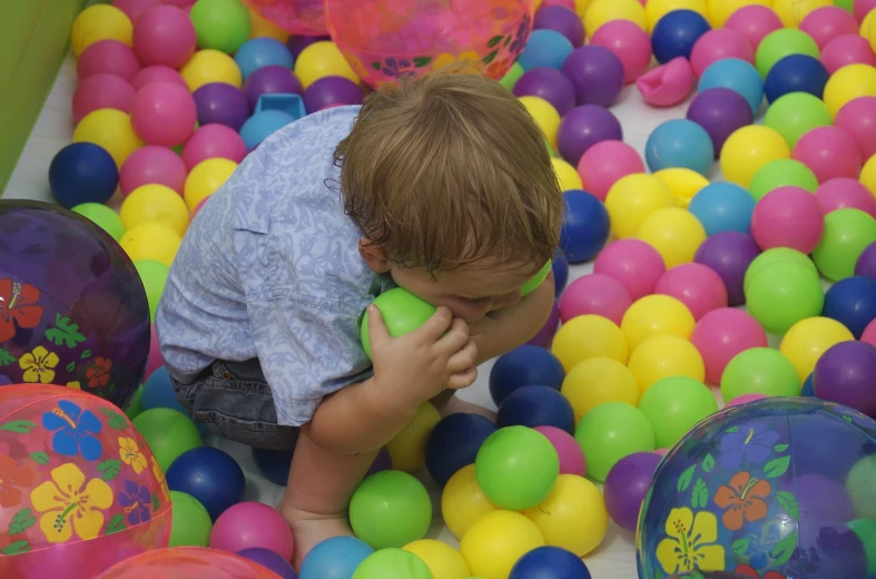 the little boy is trying to play in the ball pit