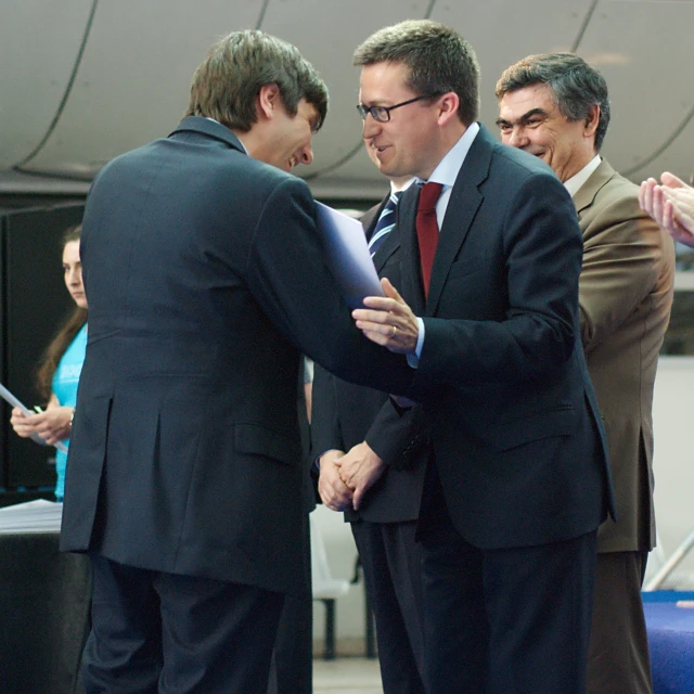 two men in business suits are holding a document