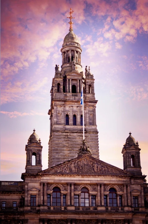 large stone clock tower and flags in front of the clouds