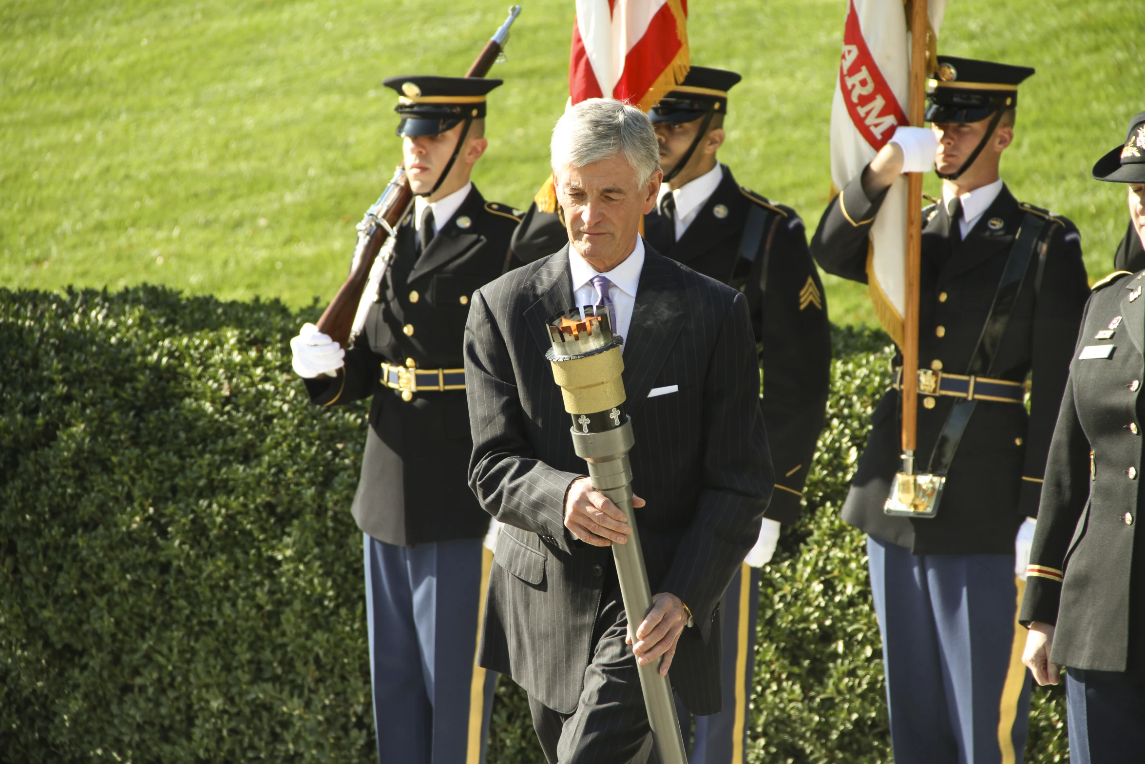 man in black suit standing on grass with flag