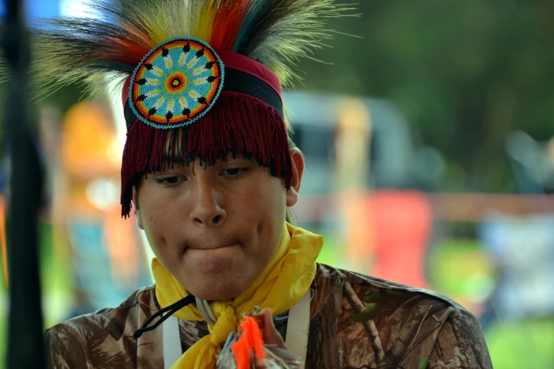 a young man is wearing a headpiece made of feathers