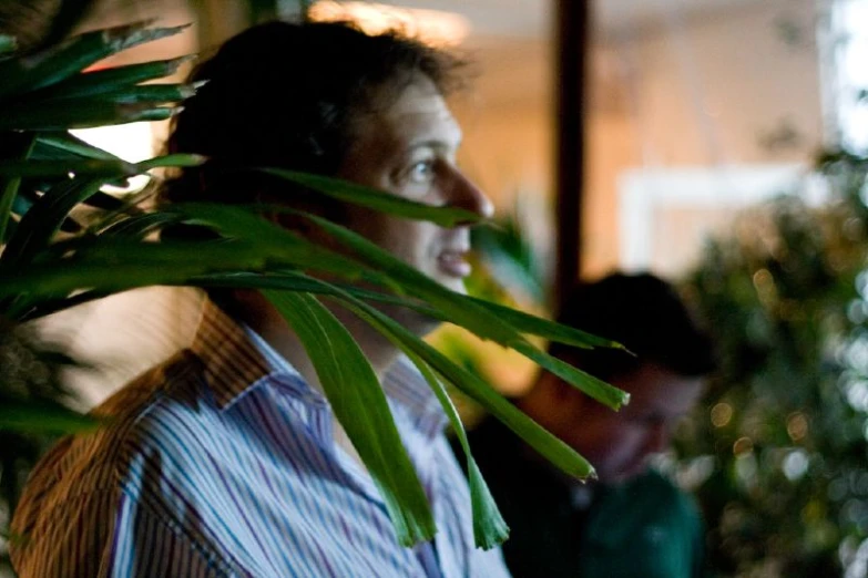 a woman is staring into the distance near a potted plant