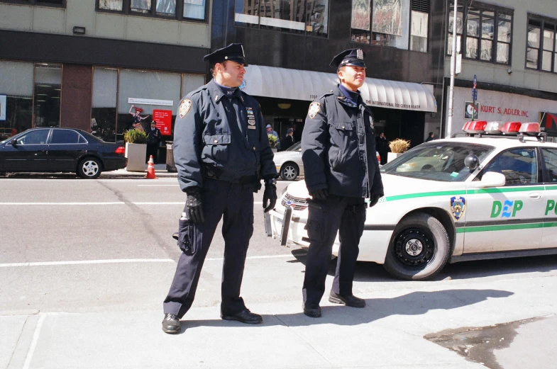 two police officers stand at the corner of a city street