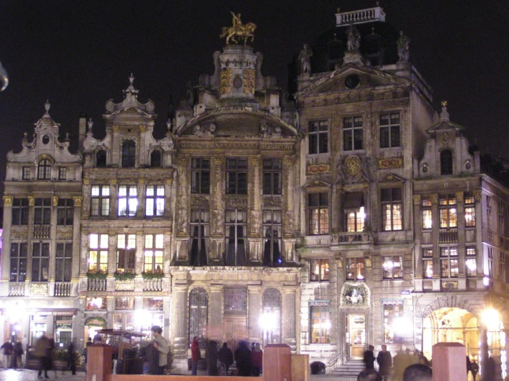 people walking around at night in front of a palace