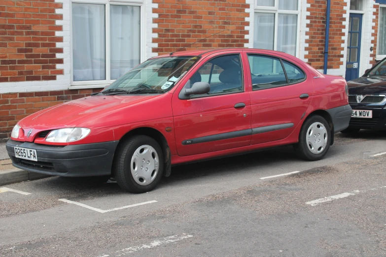 a red car sits parked next to another black one