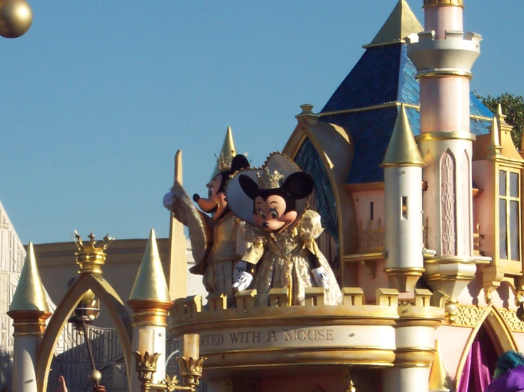 a mickey mouse statue is at the entrance of disney's castle