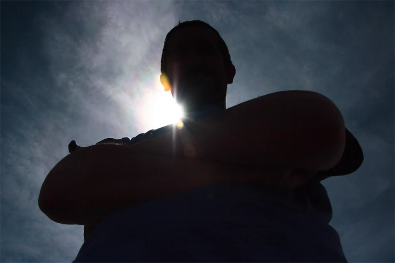 a man poses in front of the sun during the day