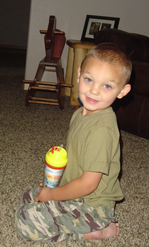 a  holding a water bottle sitting on the ground