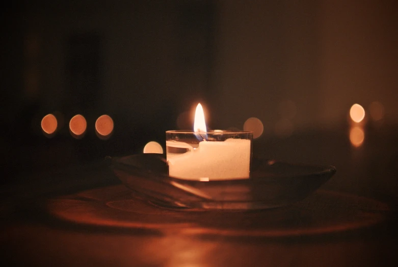 a lit candle on a plate sitting in front of other candles