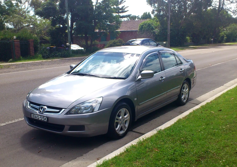 a silver car with a surfboard on top in the road