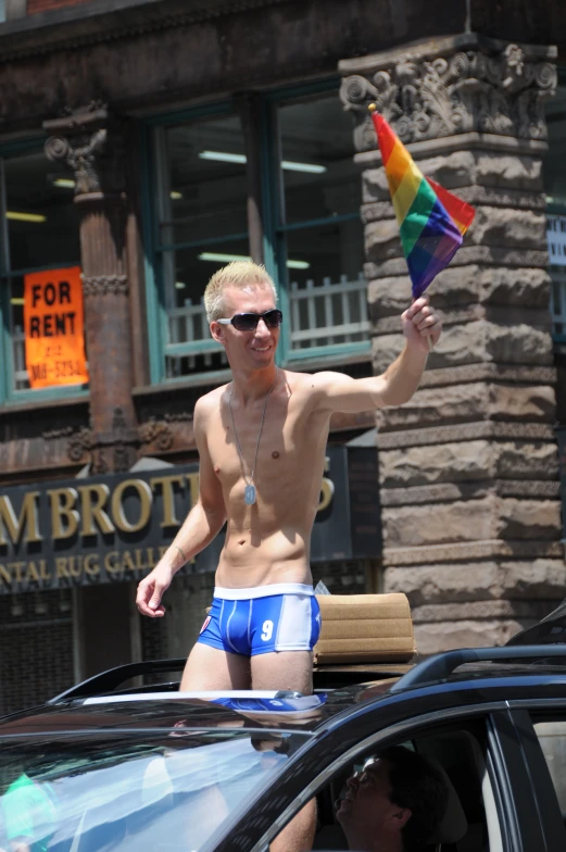 shirtless man in trunks holding up a colorful kite