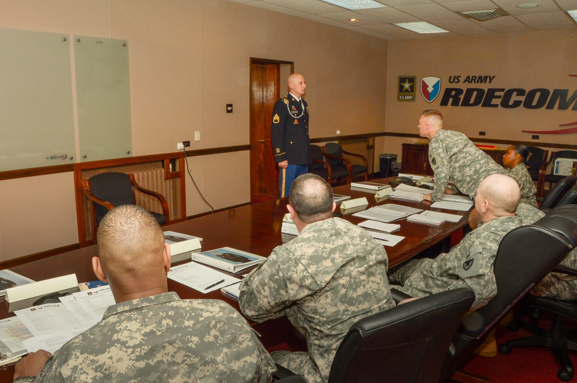 a military officer standing at a table talking to his colleagues