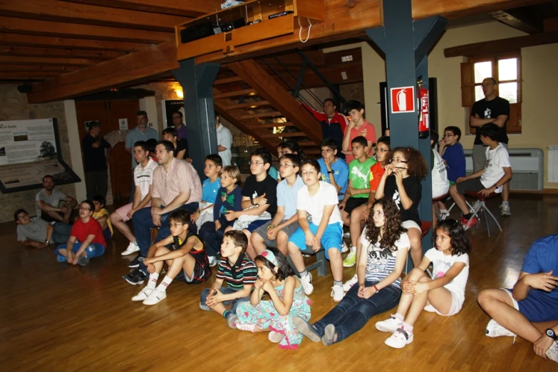 a large group of people sitting in an open space with people standing