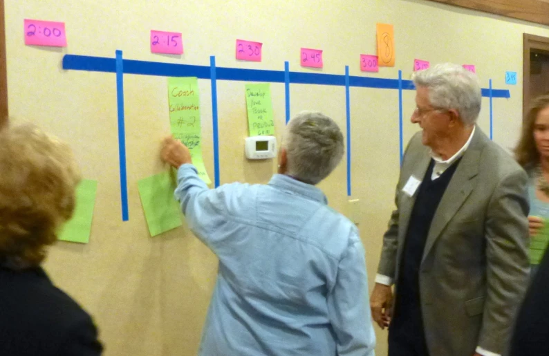 a man and woman looking at sticky notes on a wall