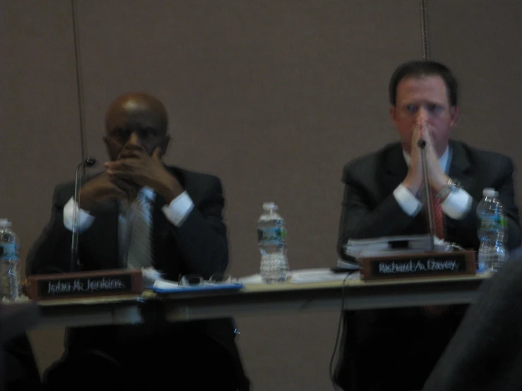 a man in a suit and tie sitting at a table with two other men