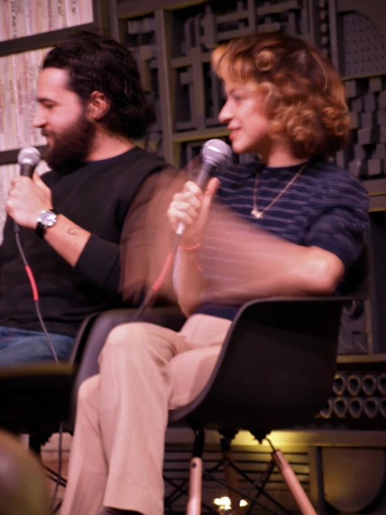 a woman and a man sit on stage with microphones